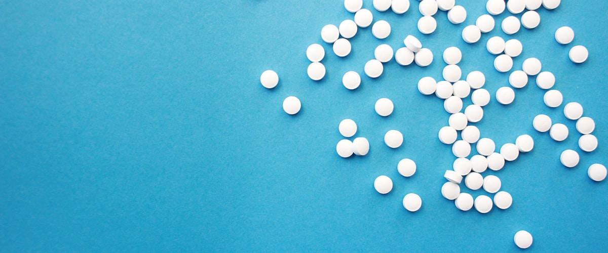 NHS pharmacy services — tablets on an NHS-blue background at Barons Court Pharmacy